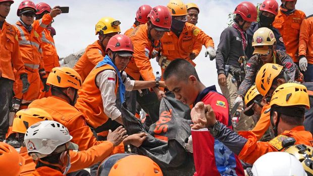 Seorang anak dalam kondisi luka dievakuasi ayahnya menuju pengungsian di Cianjur. Anak itu dievakuasi dengan cara digendong melintasi puing-puing bangunan.