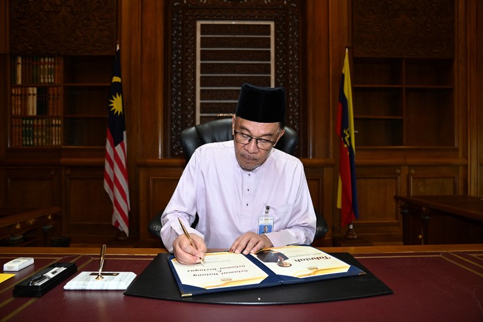 Malaysias newly appointed Prime Minister Anwar Ibrahim signing a document as he clocks in to the Prime Minister office on his first day holding the premier position at Putrajaya, Malaysia November 25, 2022. Malaysian Department of Information/Wazari Wazir/Handout via REUTERS ATTENTION EDITORS - THIS IMAGE HAS BEEN SUPPLIED BY A THIRD PARTY. NO RESALES. NO ARCHIVES. MANDATORY CREDIT