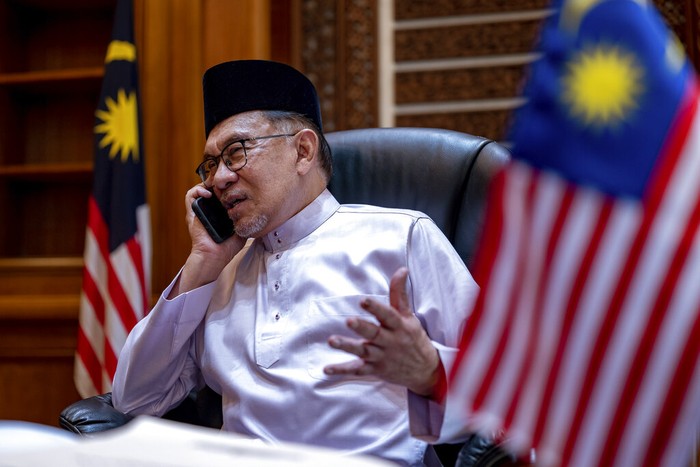 In this photo provided by Prime Minister Office, Malaysias Prime Minister Anwar Ibrahim talks on phone on his first day at the prime ministers office in Putrajaya, Malaysia, Friday, Nov. 25, 2022. (Prime Minister office via AP)