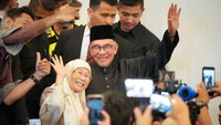 Anwar Ibrahim (tengah) dan istrinya Wan Azizah melambai saat mereka tiba sebelum pidatonya di sebuah pertemuan di Kuala Lumpur. Vincent Thian/AFP/Getty Images