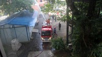 Tampak mobil pemadam kebakaran menyemprotkan air ke gedung yang terbakar.