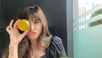 Mengonsumsi buah-buahan menjadi salah satu rahasia tubuh bugar dan idealnya. Ada semangka berukuran besar dan sebuah jeruk yang dinikmatinya sebagai camilan sehat. Foto: Instagram/angelalee87