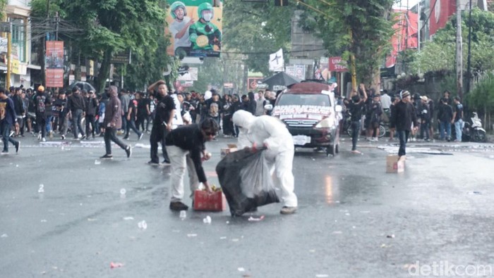 Aremania usai melakukan unjuk rasa melakukan aksi membersihkan sampah dari jalan raya