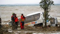 Tim penyelamat berdiri di samping bus yang terbawa arus setelah hujan lebat memicu tanah longsor yang meruntuhkan bangunan dan menyebabkan sebanyak 12 orang hilang, di Casamicciola, di pulau Ischia, Italia selatan, Italia, Sabtu (26/11/2022). AP/Salvatore Laporta 