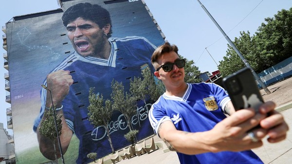 Seseorang berswafoto dengan mural legenda sepak bola Argentina Diego Armando Maradona yang dibuat oleh seniman Martin Ron.