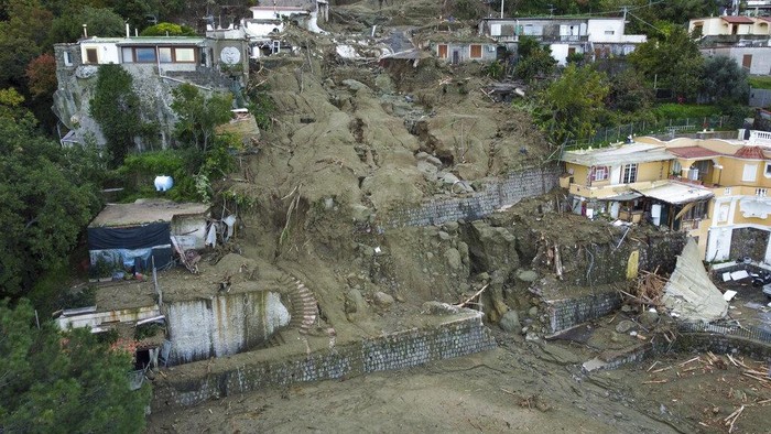 A caterpillar removes mud and debris after heavy rainfall triggered landslides that collapsed buildings and left as many as 12 people missing, in Casamicciola, on the southern Italian island of Ischia, Sunday, Nov. 27, 2022. Authorities said that the landslide that early Saturday destroyed buildings and swept parked cars into the sea left one person dead and 12 missing. (AP Photo/Salvatore Laporta)