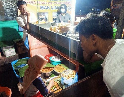 Sejumlah pembeli harus menunduk saat memesan nasi jinggo di Warung Nasi Jinggo Kolong Meja Selera Pedas Asli Pekalongan Mak Ijah di Jalan Pulau Bungin, Gang Damar Denpasar, Bali.