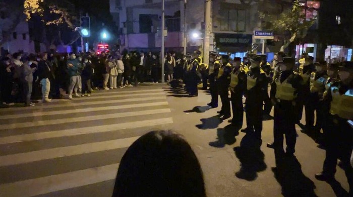 Chinese police officers block off access to a site where protesters had gathered in Shanghai on Sunday, Nov. 27, 2022. Protests against China's strict 