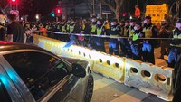 Petugas polisi berdiri di belakang barikade dan penjagaan di lokasi di mana protes terhadap pembatasan COVID-19 terjadi malam sebelumnya, setelah kebakaran Urumqi yang mematikan, di Shanghai, China, Minggu (27/11/2022). Reuters/Josh Horwitz