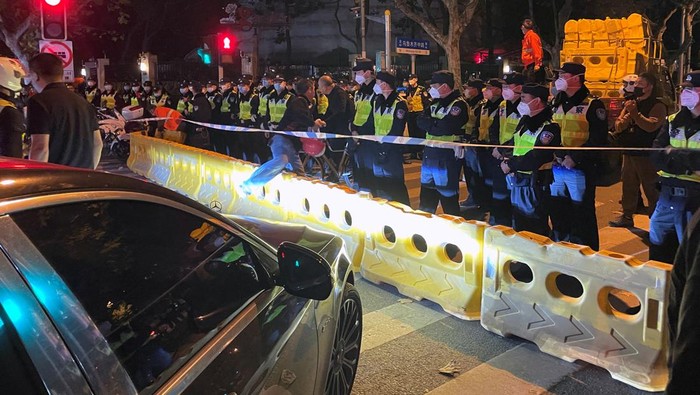 Tegang! Warga China Protes Aturan Lockdown COVID-19 Police officers stand behind barricades and cordon at the site where a protest against COVID-19 curbs took place the night before, following the deadly Urumqi fire, in Shanghai, China November 27, 2022. REUTERS/Josh Horwitz