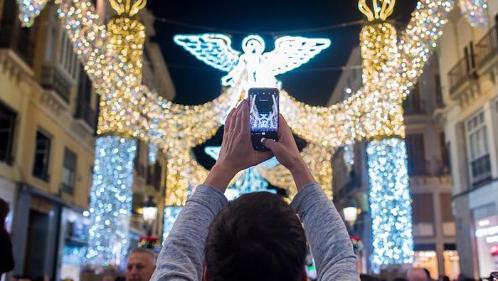 Antusias Warga Spanyol Saat Lampu-lampu Natal Menyala MALAGA, SPAIN - 2022/11/26: People are seen using their mobile phones to take pictures as they look at the lights during the switching on of the Christmas lighting at Marques de Larios street. Amid energy crisis and the increase of price electricity, Malaga city turns on its Christmas lights to mark the Christmas season, where thousands of people gather in downtown city to see a new Christmas decoration and lights show. (Photo by Jesus Merida/SOPA Images/LightRocket via Getty Images)