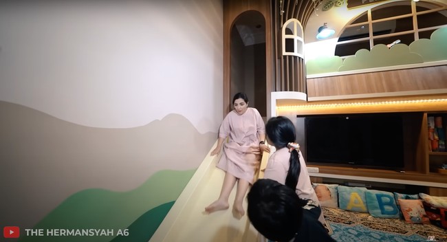 Ashanty bahkan ikut mencoba langsung menggunakan perosotan di playhouse Arsy dan Arsya. Foto: YouTube/The Hermansyah A6