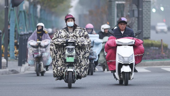 Brrr.. Warga China 'Selimutan' di Motor LIANYUNGANG, CHINA - NOVEMBER 28, 2022 - People wear thick winter clothes and ride bicycles on a street in Lianyungang city, East China's Jiangsu province, Nov 28, 2022. The Central Meteorological Observatory continued to issue an orange cold wave alert at 06:00 on November 28. The cold wave is expected to affect the central and eastern parts of China from north to south from June 28 to 30, causing severe temperature drop, strong winds, dust and widespread rain and snow. Most areas in central and eastern China will see a drop in temperature of 10 to 16, and some areas will see a drop in temperature of more than 18. (Photo credit should read CFOTO/Future Publishing via Getty Images)