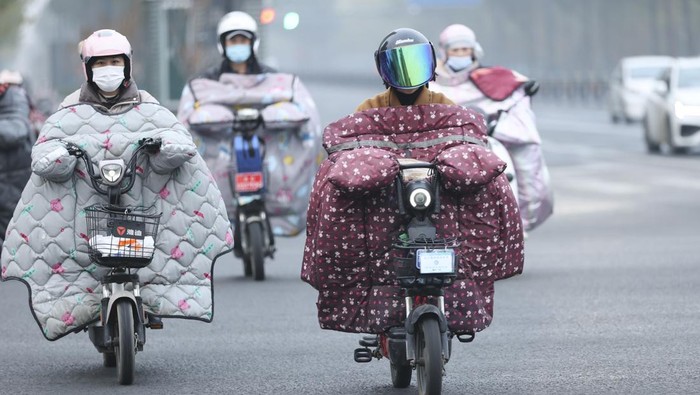 LIANYUNGANG, CHINA - NOVEMBER 28, 2022 - People wear thick winter clothes and ride bicycles on a street in Lianyungang city, East China's Jiangsu province, Nov 28, 2022. The Central Meteorological Observatory continued to issue an orange cold wave alert at 06:00 on November 28. The cold wave is expected to affect the central and eastern parts of China from north to south from June 28 to 30, causing severe temperature drop, strong winds, dust and widespread rain and snow. Most areas in central and eastern China will see a drop in temperature of 10 to 16, and some areas will see a drop in temperature of more than 18. (Photo credit should read CFOTO/Future Publishing via Getty Images)