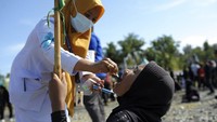 Seorang pekerja medis memberikan vaksin kepada seorang anak.