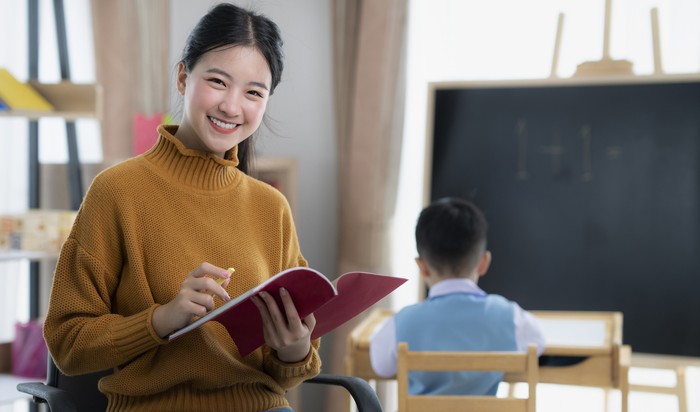 Asian teacher At preschool Helping Children in Class in class room