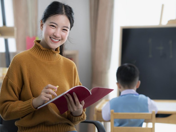 Asian teacher At preschool Helping Children in Class in class room
