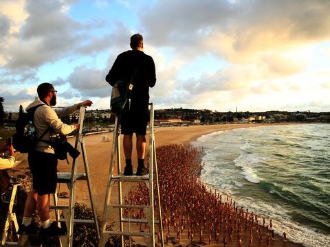 SYDNEY, AUSTRALIA - NOVEMBER 26: (EDITORS NOTE: Image contains nudity.) Spencer Tunick is seen photographing members of the public posing  at Bondi Beach on November 26, 2022 in Sydney, Australia. US artist and photographer Spencer Tunick created the nude installation using thousands of volunteers posing at sunrise on Bondi Beach, commissioned by charity Skin Check Champions to raise awareness of skin cancer and to coincide with National Skin Cancer Action Week. (Photo by Don Arnold/WireImage)
