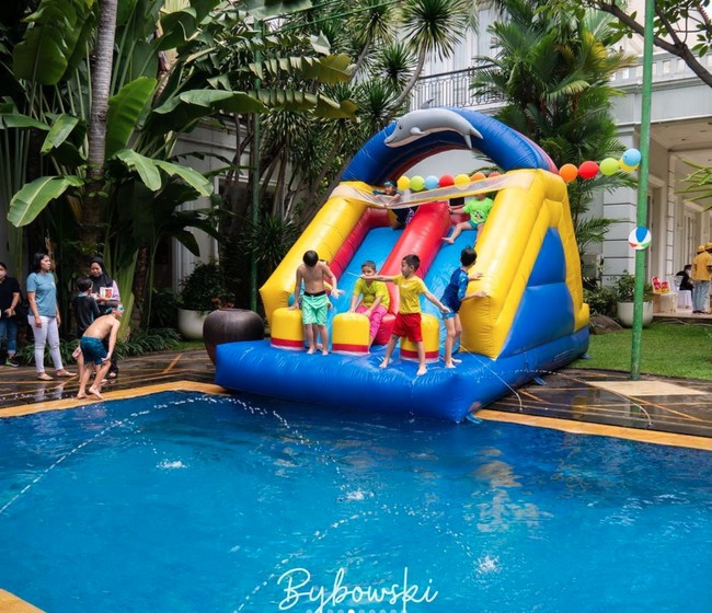 Beragam mainan anak tampak tersedia di pesta ulang tahun Mainaka. Salah satunya adalah mainan perosotan yang satu ini. Terlihat anak-anak yang hadir sangat senang bermain di perosotan yang langsung terhubung dengan kolam renang tersebut. Foto: Instagram/@ramadhaniabakrie