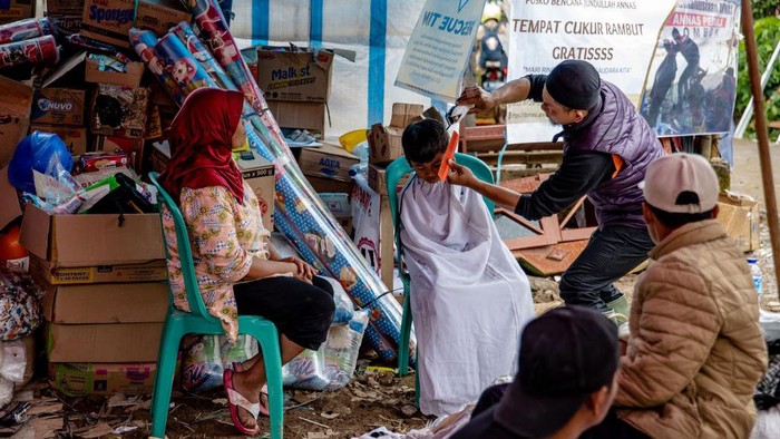 Salah satu warga membuat tempat pangkas gratis di dalam tenda darurat gempa untuk para warga yang ingin mencukur rambutnya. Lihat nih.