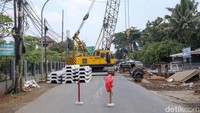 Tampak alat berat yang tengah melakukan pelebaran melintang di tengah jalan.