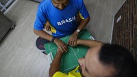 Helio memandu temannya yang bernama Carlos itu melalui papan kayu yang dibuatnya untuk menggambarkan pertandingan yang terjadi. (Foto: AP/Marcelo Chello)