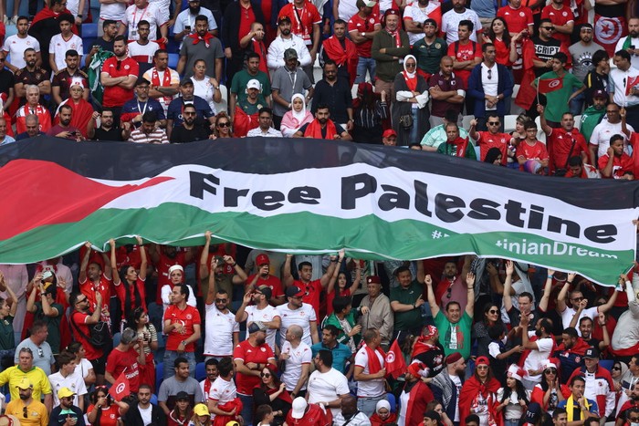 AL WAKRAH, QATAR - NOVEMBER 26:  Fans hold a Flag of Palestine with Free Palestine written on it during the FIFA World Cup Qatar 2022 Group D match between Tunisia and Australia at Al Janoub Stadium on November 26, 2022 in Al Wakrah, Qatar. (Photo by James Williamson - AMA/Getty Images)