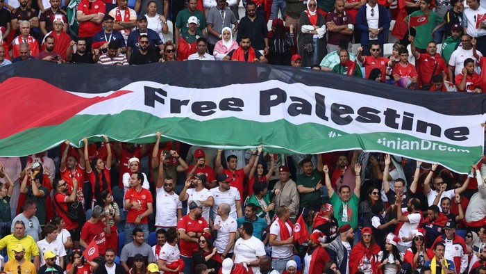 AL WAKRAH, QATAR - NOVEMBER 26:  Fans hold a Flag of Palestine with Free Palestine written on it during the FIFA World Cup Qatar 2022 Group D match between Tunisia and Australia at Al Janoub Stadium on November 26, 2022 in Al Wakrah, Qatar. (Photo by James Williamson - AMA/Getty Images)