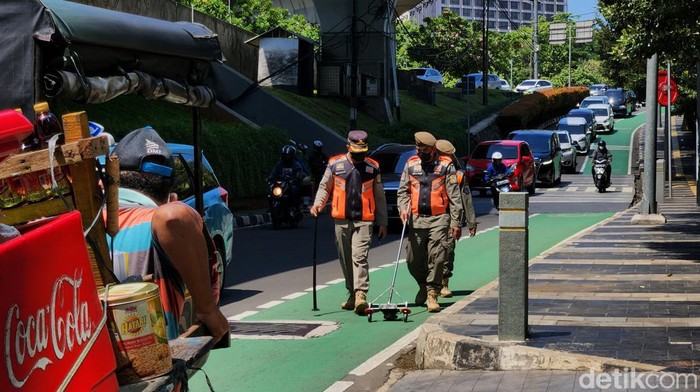 Jalur Sepeda Disisir Petugas, Ada Apa? Petugas Satpol PP melakukan pada jalur sepeda di kawasan Semanggi. Aksi tersebut dilakukan untuk memastikan jalur sepeda aman dari ranjau paku dan serpihan benda tajam.