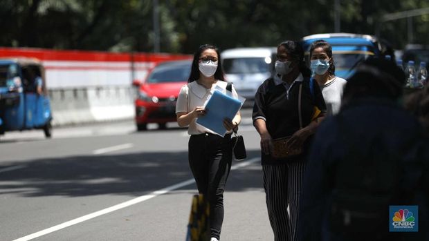 Sejumlah karyawan melewati jembatan penyeberangan orang (JPO) di kawasan Sudirman, Jakarta, Selasa (29/11/2022). Kepala Disnakertrans provinsi DKI Jakarta Andri Yansyah mengungkapkan kenaikan UMP 2023 DKI Jakarta sebesar 5,6% ke Rp 4.901.798.  (CNBC Indonesia/Tri Susilo)