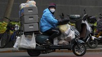 Kurir mengantarkan pesanan online menggunakan sepeda motor.
