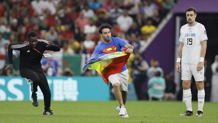 LUSAIL CITY, QATAR - NOVEMBER 28: Fan runs on pitch with rainbow flag during the FIFA World Cup Qatar 2022 Group H match between Portugal v Uruguay at Al Janoub Stadium on November 28, 2022 in Lusail City, Qatar. (Photo by Richard Sellers/Getty Images)