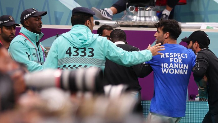 LUSAIL CITY, QATAR - NOVEMBER 28:  A protester on the pitch with rainbow flag and free Ukraine T shirt and is escorted away by security during the FIFA World Cup Qatar 2022 Group H match between Portugal and Uruguay at Lusail Stadium on November 28, 2022 in Lusail City, Qatar. (Photo by Marc Atkins/Getty Images)