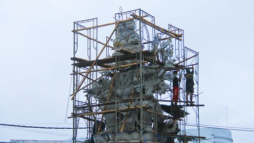 Seorang pekerja sedang merekatkan bagian kepala patung Wisnu Murti di bundaran Kediri dan mempersiapkan sejumlah rangka untuk memasang bagian detil, Selasa (29/11/2022). Foto: Chairul Amri Simabur