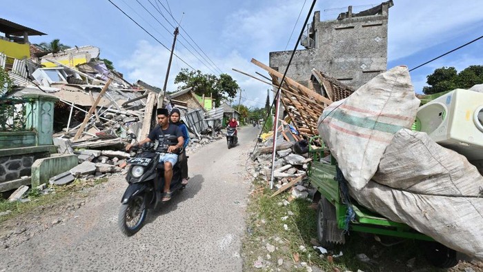 TOPSHOT - Motorists ride past collapsed and damaged houses in Cugenang, Cianjur on November 23, 2022, following a 5.6-magnitude earthquake that hit the area on November 21. - Survivors of an Indonesian earthquake that killed at least 268 people appealed for food and water on November 23 as rescuers picked through devastated villages, with hopes fading of finding anyone alive. (Photo by ADEK BERRY / AFP) (Photo by ADEK BERRY/AFP via Getty Images)