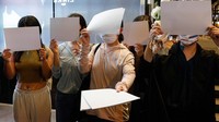 Orang-orang memegang lembaran kertas kosong untuk memprotes pembatasan COVID di Urumqi, Hong Kong, China, Senin (28/11).
