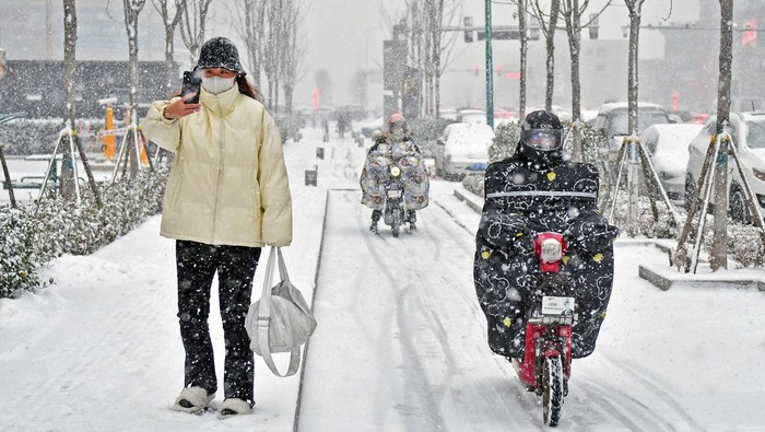 YANTAI, CHINA - NOVEMBER 17, 2022 - People brave snow on a street in Yantai, Shandong province, China, Nov 30, 2022. (Photo credit should read CFOTO/Future Publishing via Getty Images)