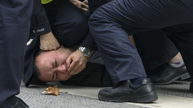 In this photo taken on Sunday, Nov. 27, 2022, policemen pin down and arrest a protester during a protest on a street in Shanghai, China. Authorities eased anti-virus rules in scattered areas but affirmed China's severe 