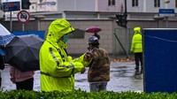Polisi (berbaju kuning) berjaga di jalan Wulumuqi. Aksi demonstrasi semacam ini dianggap langka di China, negara dengan sistem sensor dan keamanan yang ketat. Ini pun disebut-sebut sebagai aksi demonstrasi terbesar sejak insiden Tiananmen pada 1989 silam. Hector Retamal/AFP/Getty Images