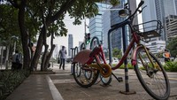 Warga melintas di dekat sepeda sewa yang rusak di Jalan Jenderal Sudirman, Jakarta, Selasa (29/11/2022).