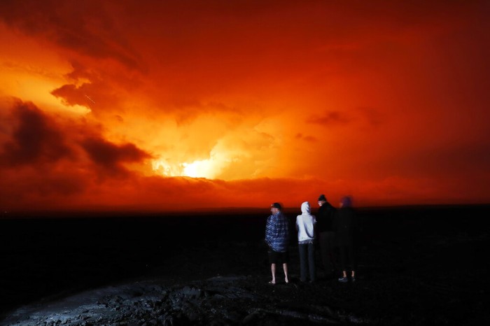 People watch the eruption of Mauna Loa, Monday, Nov. 28, 2022, near Hilo, Hawaii. Mauna Loa, the worlds largest active volcano erupted Monday for the first time in 38 years. (AP Photo/Marco Garcia)