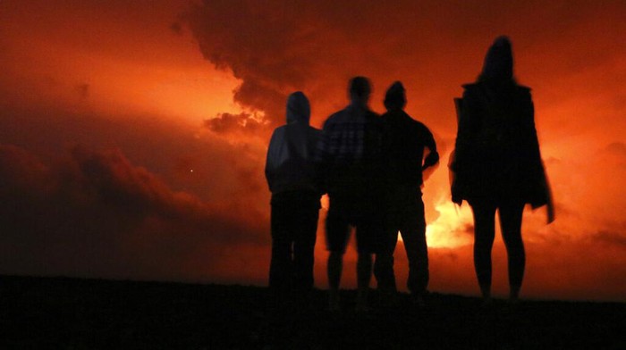 People watch the glow from lava erupting from Hawaii's Mauna Loa volcano, Monday, Nov. 28, 2022 in Hilo, Hawaii. (AP Photo/Caleb Jones)