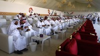 Orang-orang sedang menyaksikan kontes kecantikan unta di Qatar Camel Mzayen Club dari balik kaca sekaligus memberikan penilaian.   