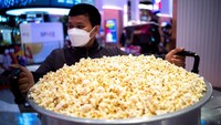 Seorang pria membawa panci berisi popcorn saat kampanye makan popcorn sepuasnya.  