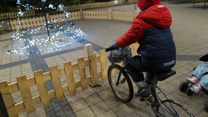 A boy cycles a charging bicycle to light the Christmas tree in Budapest, Hungary, Tuesday Nov. 29, 2022. By using charging bicycles, everyone can experience the energy needed to light up Christmas decoration. The money saved by the municipality on the unusual decorative lighting will be used to increase grants for residents living in difficult circumstances. (AP Photo/Bela Szandelszky)