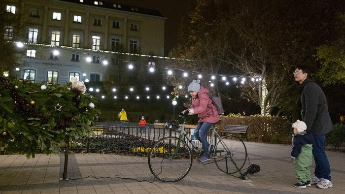 A boy cycles a charging bicycle to light the Christmas tree in Budapest, Hungary, Tuesday Nov. 29, 2022. By using charging bicycles, everyone can experience the energy needed to light up Christmas decoration. The money saved by the municipality on the unusual decorative lighting will be used to increase grants for residents living in difficult circumstances. (AP Photo/Bela Szandelszky)
