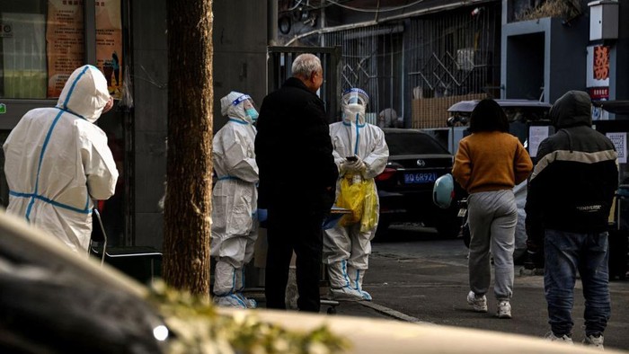 Workers wearing personal protective equipment (PPE) are seen by the entrance to a residential area under lockdown due to Covid-19 coronavirus restrictions in Beijing on November 29, 2022. (Photo by Noel CELIS / AFP) (Photo by NOEL CELIS/AFP via Getty Images)