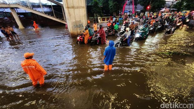 Pemotor menuntun kendaraannya untuk menerobos banjir di Jalan Ciledug Raya, Kelurahan Petukangan, Kecamatan Pesanggrahan, Jakarta Selatan, Kamis (1/12/2022). Banjir akibat hujan deras. Foto diambil pukul 18.00 WIB.