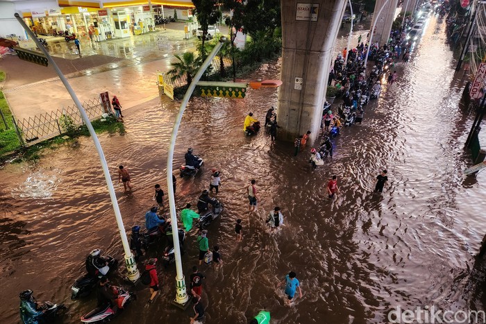 Pemotor menuntun kendaraannya untuk menerobos banjir di Jalan Ciledug Raya, Kelurahan Petukangan, Kecamatan Pesanggrahan, Jakarta Selatan, Kamis (1/12/2022). Banjir akibat hujan deras. Foto diambil pukul 18.00 WIB.