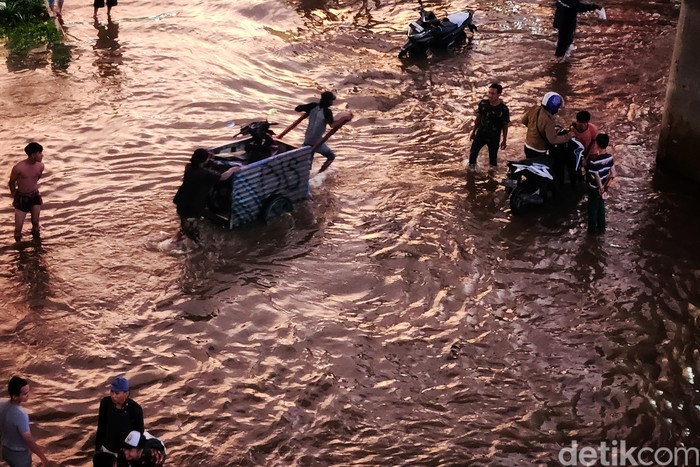 Banjir Juga Bikin Jalan Ciledug Kelelep Pemotor menuntun kendaraannya untuk menerobos banjir di Jalan Ciledug Raya, Kelurahan Petukangan, Kecamatan Pesanggrahan, Jakarta Selatan, Kamis (1/12/2022). Banjir akibat hujan deras. Foto diambil pukul 18.00 WIB.